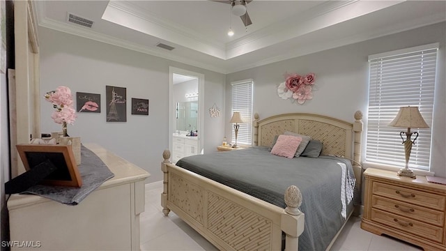 bedroom featuring light tile patterned flooring, visible vents, a raised ceiling, ensuite bath, and crown molding