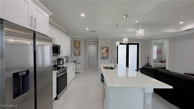 kitchen with a spacious island, appliances with stainless steel finishes, light countertops, french doors, and a sink