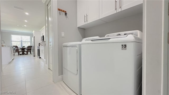 clothes washing area with light tile patterned floors, visible vents, cabinet space, and washer and dryer