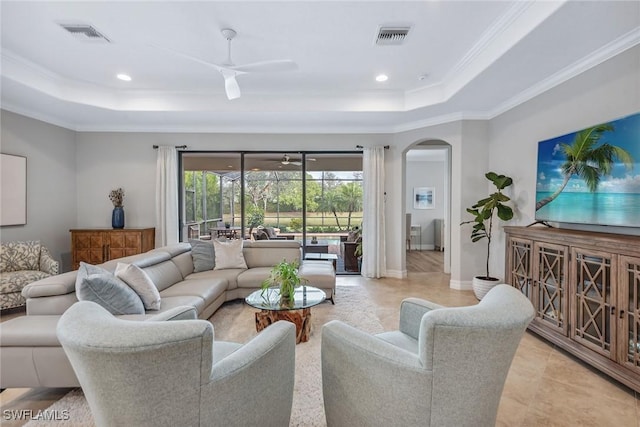 living room featuring a ceiling fan, a tray ceiling, visible vents, and crown molding