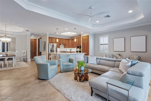 living area with ceiling fan, recessed lighting, visible vents, a tray ceiling, and crown molding