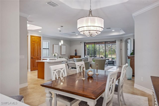 dining area featuring a chandelier, a tray ceiling, visible vents, and crown molding