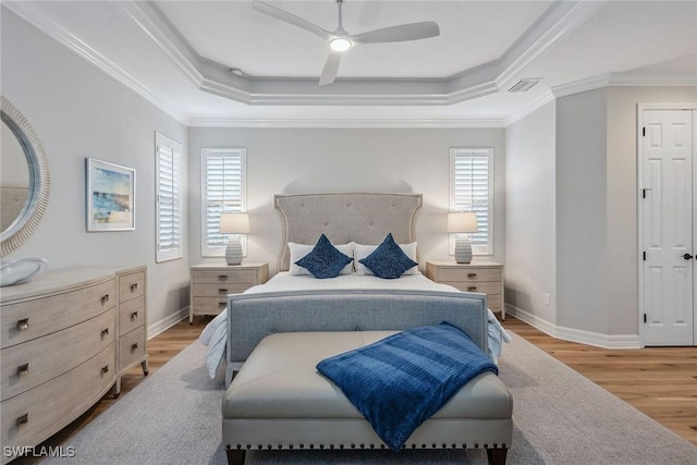 bedroom featuring wood finished floors, multiple windows, and a raised ceiling