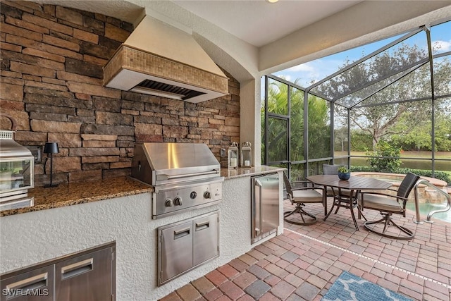 view of patio featuring glass enclosure, exterior kitchen, outdoor dining area, and area for grilling