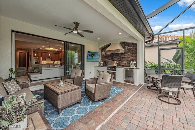 view of patio / terrace featuring ceiling fan, glass enclosure, outdoor lounge area, area for grilling, and exterior kitchen