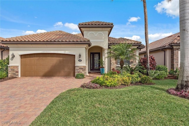 mediterranean / spanish-style house featuring a garage, stone siding, decorative driveway, and a front yard