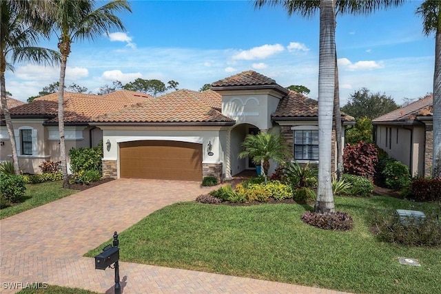 mediterranean / spanish-style house featuring a garage, stone siding, decorative driveway, a front yard, and stucco siding