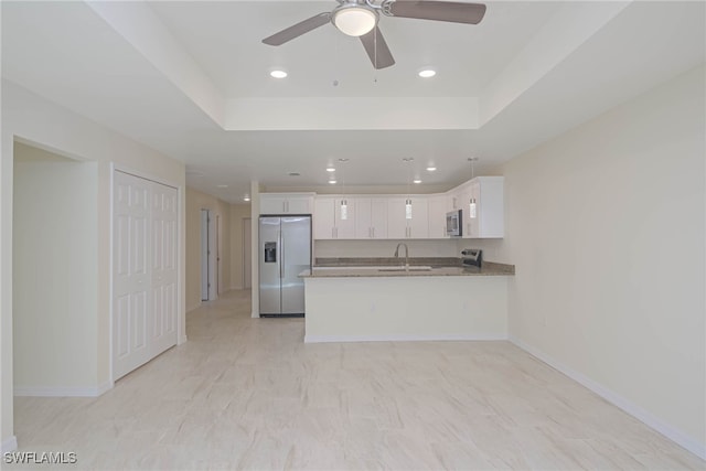 kitchen featuring appliances with stainless steel finishes, white cabinetry, a sink, light stone countertops, and a peninsula