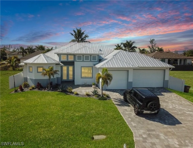 view of front of house featuring a garage, a front lawn, metal roof, and decorative driveway