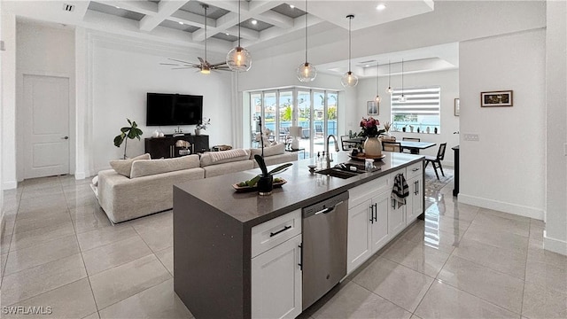 kitchen with dishwasher, dark countertops, open floor plan, white cabinetry, and a sink