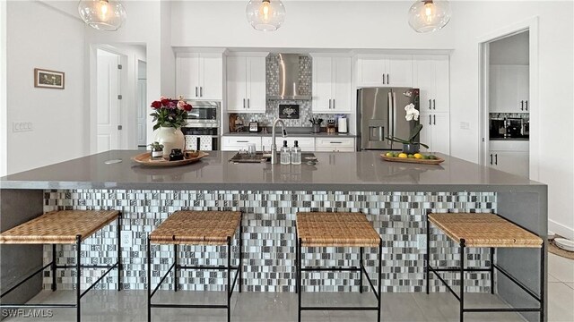 kitchen with stainless steel appliances, white cabinets, a kitchen breakfast bar, backsplash, and dark countertops