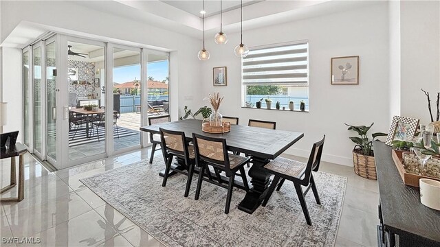 dining area featuring baseboards, a raised ceiling, a ceiling fan, a water view, and french doors