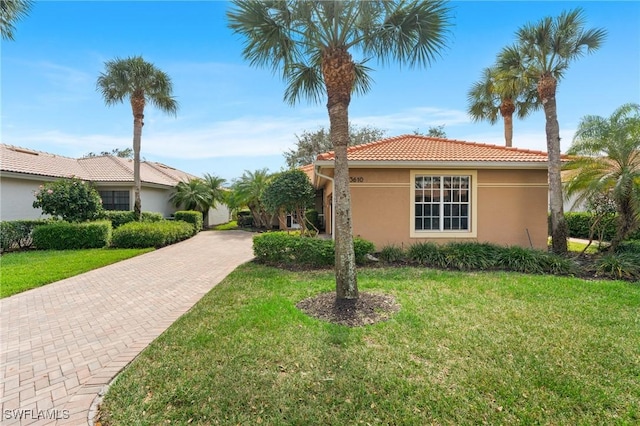 view of front of property with a front yard, a tile roof, and stucco siding