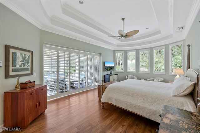 bedroom with ceiling fan, wood finished floors, visible vents, a raised ceiling, and crown molding