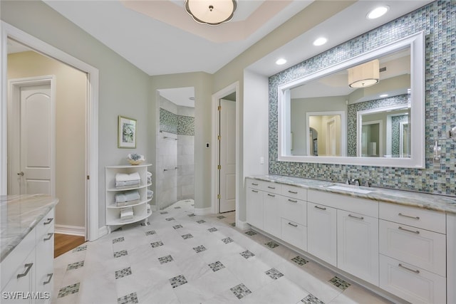 bathroom featuring backsplash, walk in shower, vanity, and baseboards