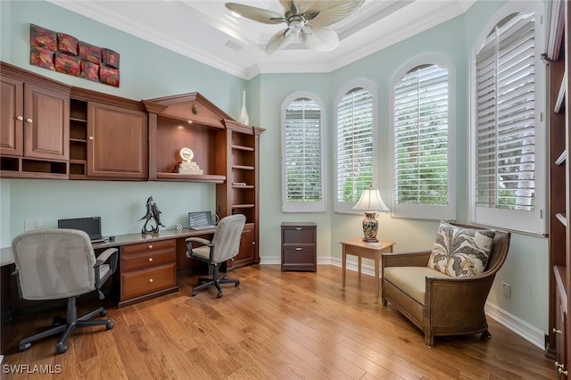 home office with ornamental molding, a tray ceiling, a healthy amount of sunlight, and light wood finished floors