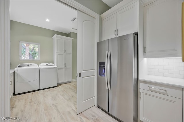 kitchen featuring light wood finished floors, light countertops, white cabinets, separate washer and dryer, and stainless steel fridge