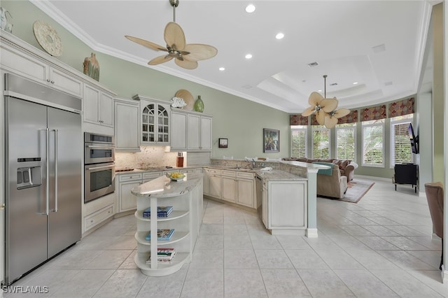 kitchen featuring stainless steel appliances, a peninsula, open shelves, a tray ceiling, and crown molding