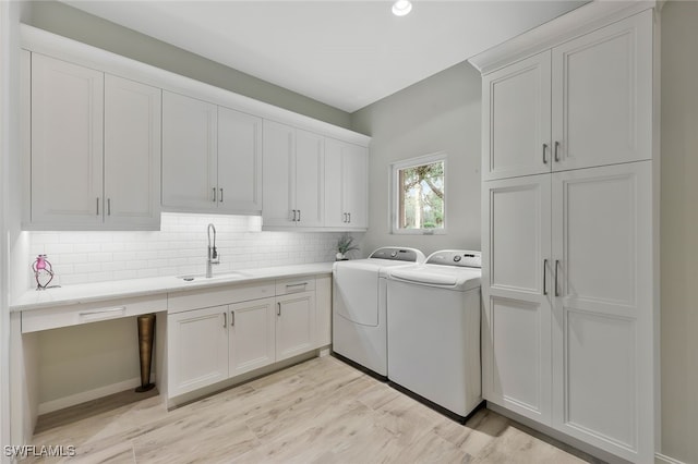 laundry room with cabinet space, light wood-style floors, separate washer and dryer, and a sink