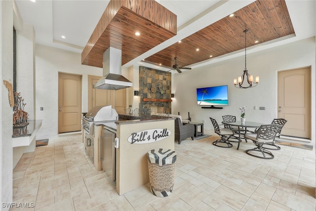 kitchen featuring wood ceiling, a center island with sink, island range hood, and a tray ceiling