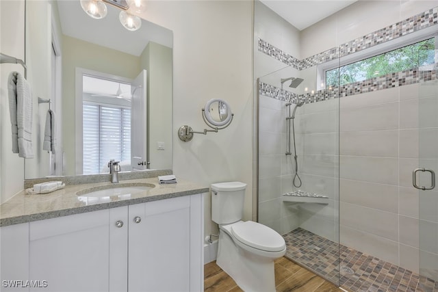 full bath with a stall shower, vanity, toilet, and wood finished floors