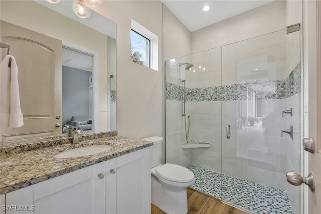 full bathroom featuring vanity, a shower stall, toilet, and wood finished floors