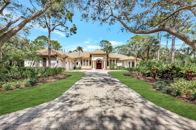 mediterranean / spanish-style house featuring a garage, decorative driveway, and stucco siding