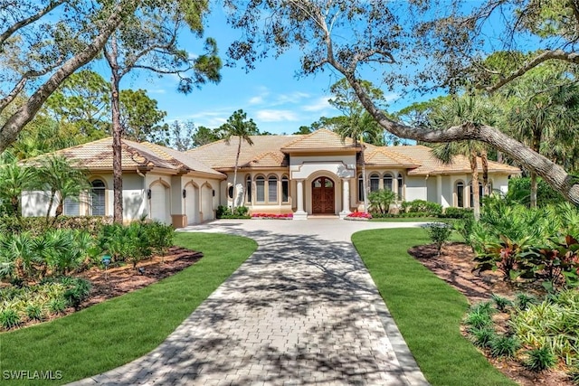 12303 Colliers Reserve Dr, Naples, FL 34110 - mediterranean / spanish-style house featuring a garage, driveway, a front lawn, and stucco siding
