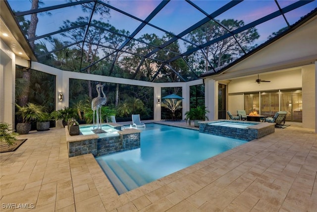 view of swimming pool featuring glass enclosure, a pool with connected hot tub, ceiling fan, and a patio