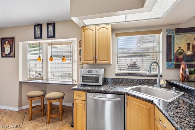 kitchen featuring light brown cabinets, a sink, a wealth of natural light, dishwasher, and dark countertops