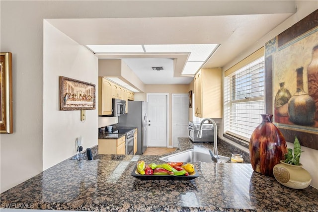 kitchen with visible vents, dark countertops, a peninsula, stainless steel appliances, and a sink