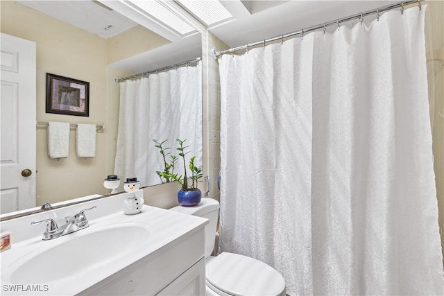 bathroom with a skylight, vanity, and toilet