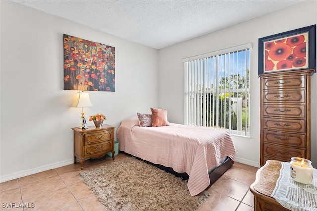 bedroom featuring a textured ceiling, light tile patterned floors, and baseboards