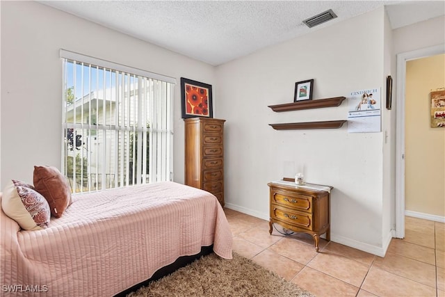 bedroom with visible vents, a textured ceiling, baseboards, and light tile patterned floors