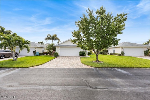 single story home with an attached garage, decorative driveway, and a front yard