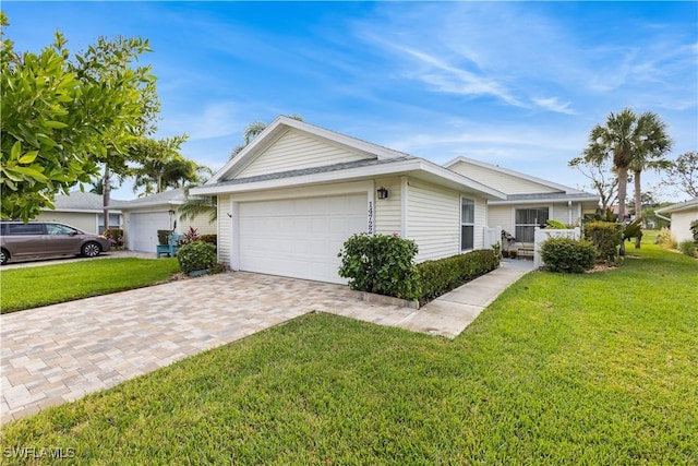 ranch-style home with a front lawn, decorative driveway, and an attached garage