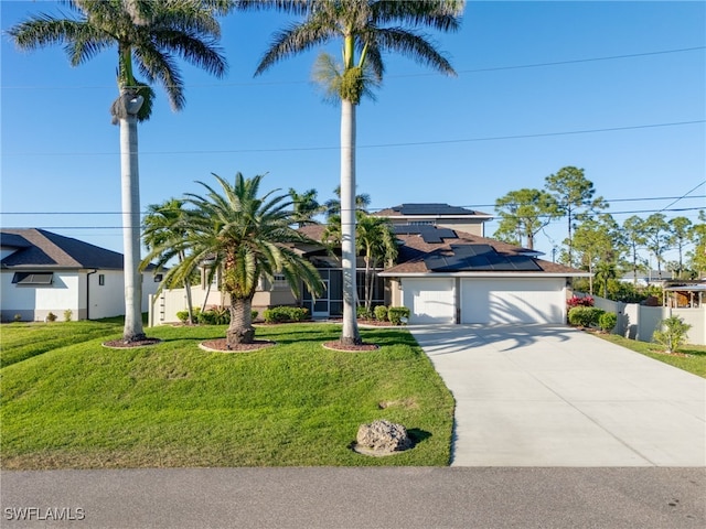 view of front of home featuring a garage, a front yard, solar panels, and concrete driveway