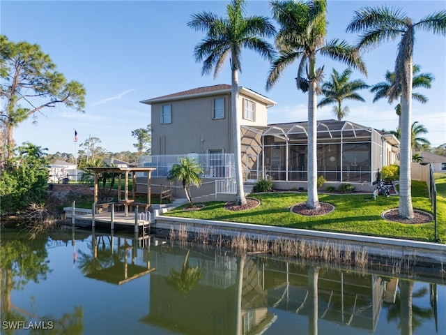 back of house featuring a water view, glass enclosure, a lawn, and stucco siding