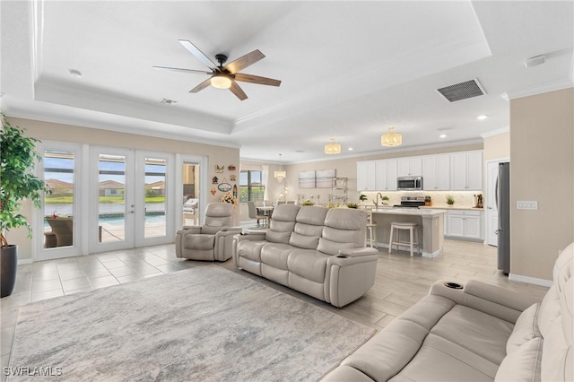 living room with french doors, a raised ceiling, visible vents, ornamental molding, and ceiling fan