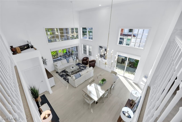 living room with a chandelier, a towering ceiling, and hardwood / wood-style floors