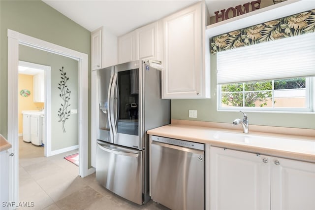 kitchen with washing machine and dryer, white cabinetry, stainless steel appliances, and light countertops