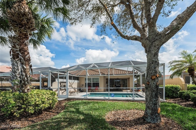 back of house featuring glass enclosure and an outdoor pool