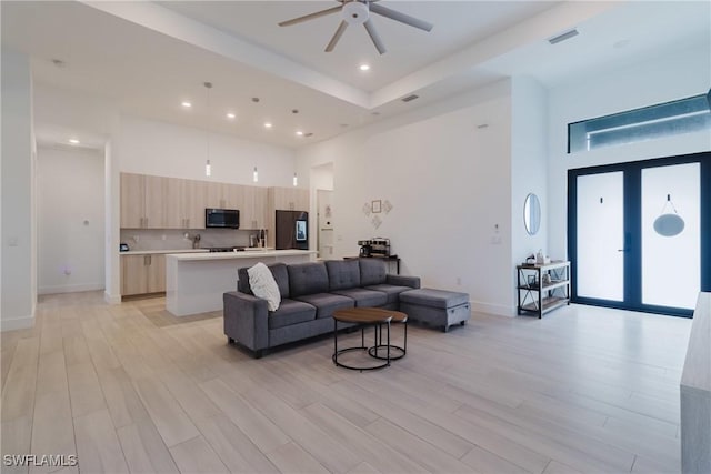 living area with light wood finished floors, french doors, and a high ceiling