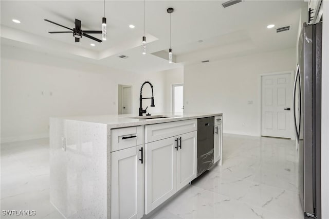 kitchen with an island with sink, white cabinetry, a raised ceiling, and freestanding refrigerator