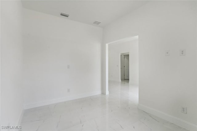 spare room with marble finish floor, visible vents, and baseboards