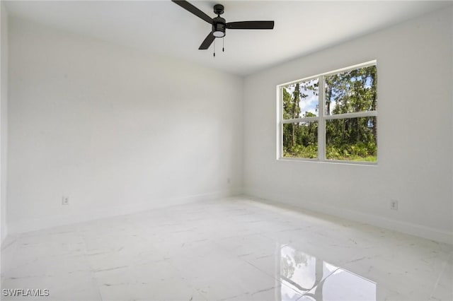 empty room with marble finish floor, baseboards, and a ceiling fan