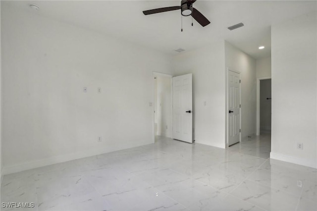 empty room featuring ceiling fan, marble finish floor, visible vents, and baseboards