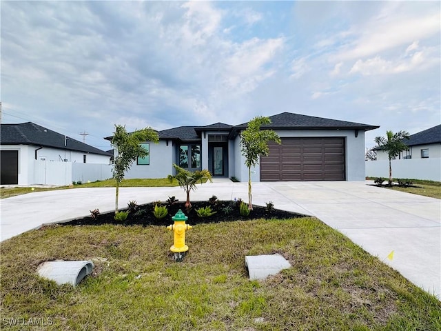 prairie-style home with a garage, stucco siding, concrete driveway, and a front yard