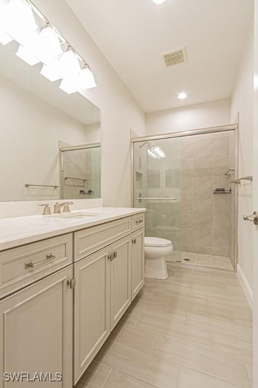 bathroom with a shower with shower door, vanity, and toilet