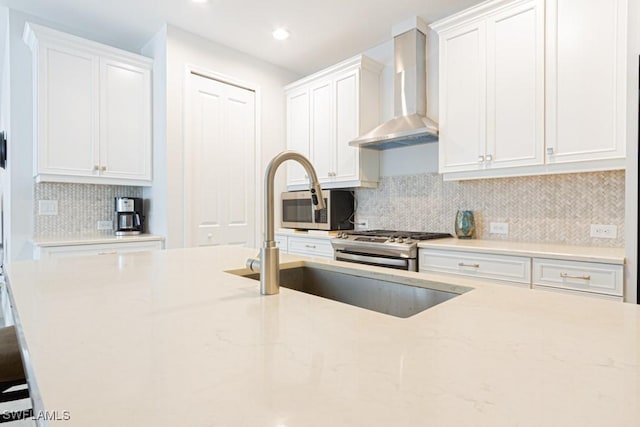 kitchen with light stone counters, white cabinets, tasteful backsplash, and wall chimney exhaust hood